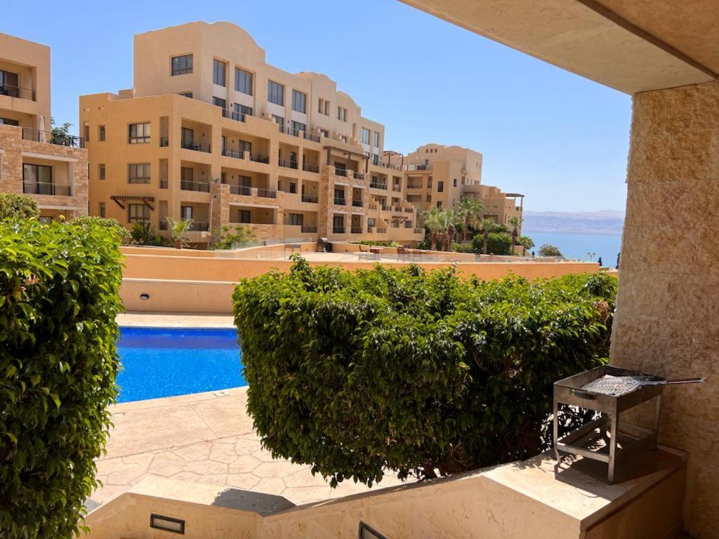 索瓦馬的住宿－Apartment at Samarah Dead Sea Resort，从带游泳池的大楼的阳台上可欣赏到风景