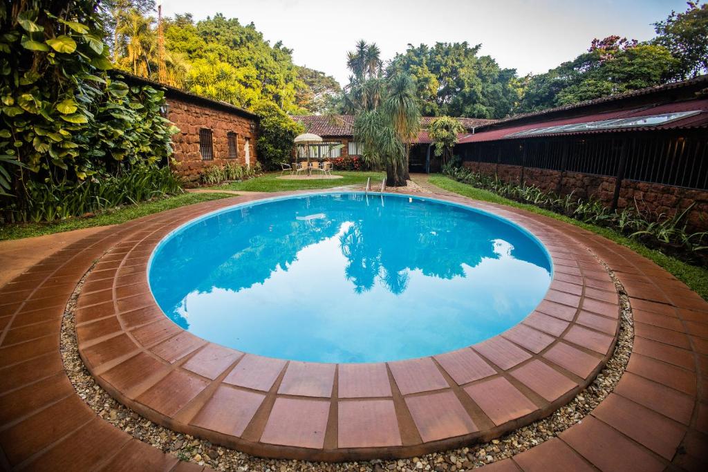 einen Pool in einem Garten mit einem Backsteingebäude in der Unterkunft Paineiras Hotel Fazenda in Uberaba