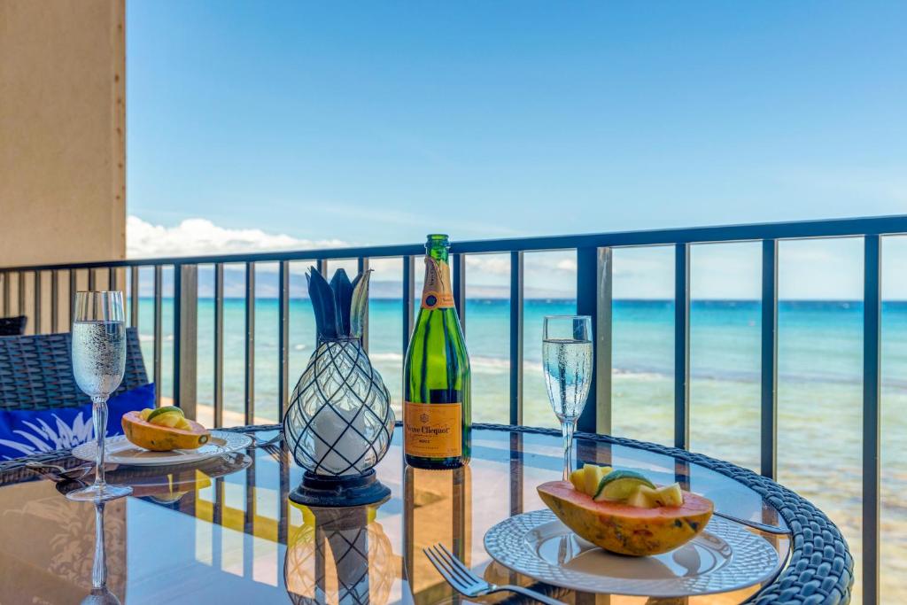 un tavolo in vetro con una bottiglia di vino sul balcone di Nohonani 203 a Kahana