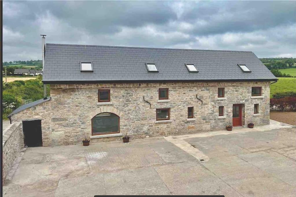 - un grand bâtiment en pierre avec des fenêtres et un toit dans l'établissement Tom Rocky’s Farmyard, à Templemore