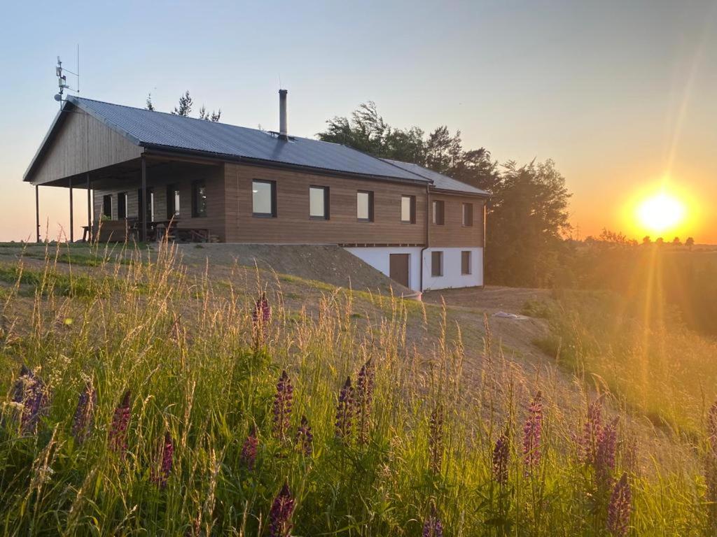 a house on a hill with the sunset in the background at Restaurace a penzion Gansberg in Cotkytle