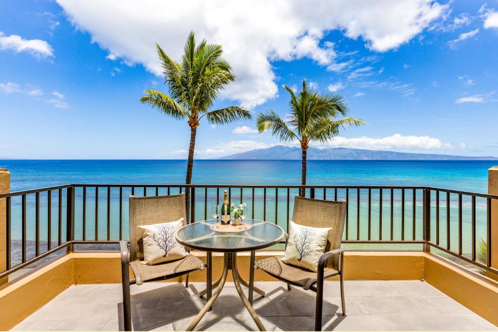 a balcony with a table and chairs and the ocean at Paki Maui 403 in Kahana