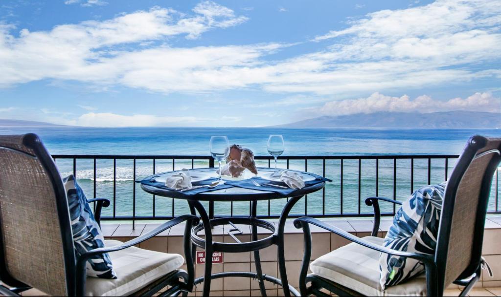 a table and chairs on a balcony with a view of the ocean at Maui Kai 504 in Kahana