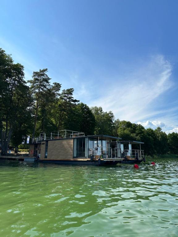 a house on a boat on a body of water at Domki na wodzie - Resort 36 Houseboats in Giżycko