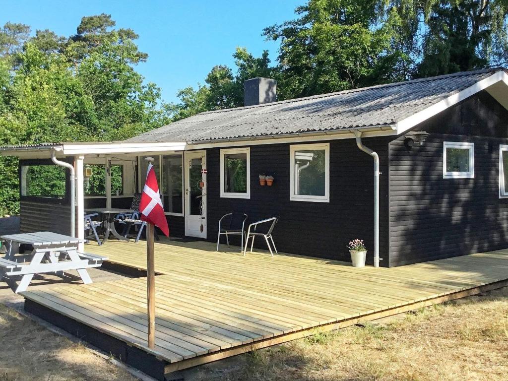 ein Haus mit einer Holzterrasse mit einer Flagge darauf in der Unterkunft Holiday home Rønde XXIV in Rønde