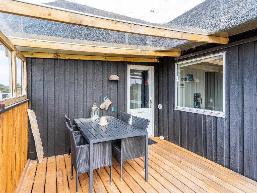 a patio with a table and chairs on a deck at Holiday home Hvide Sande LXIX in Havrvig