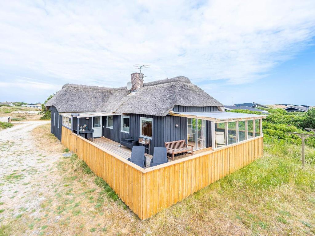 a house with a thatched roof on a beach at Holiday home Hvide Sande LXIX in Havrvig