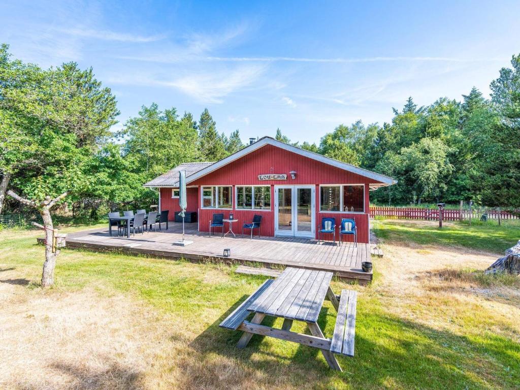 a red house with a picnic bench in front of it at Holiday home Blåvand CCXXXVIII in Blåvand