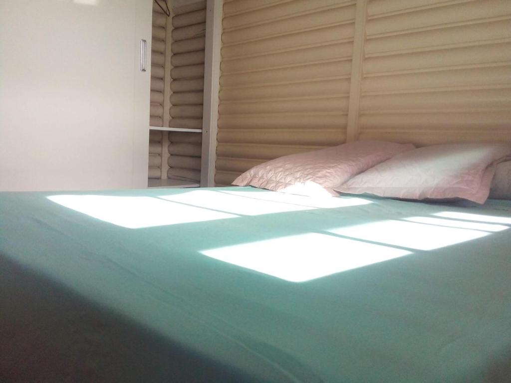 un dormitorio con una cama con el sol brillando sobre ella en Chalé alpino mobiliado perto do centro de canela rs en Canela