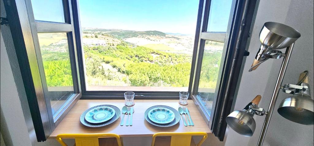 una mesa con sillas y platos y una ventana en Casa Bakara balcón de Vejer, en Vejer de la Frontera
