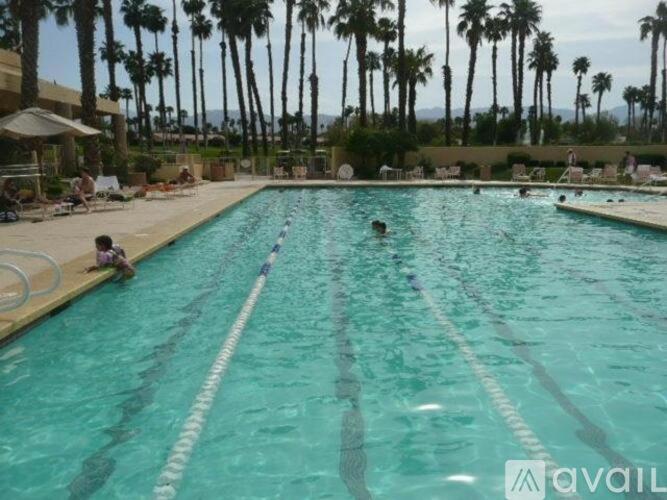 a large swimming pool with two children in the water at Palm Valley CC 2 Bdrms Den 2 Ba Lux Condo Best Location in Palm Desert