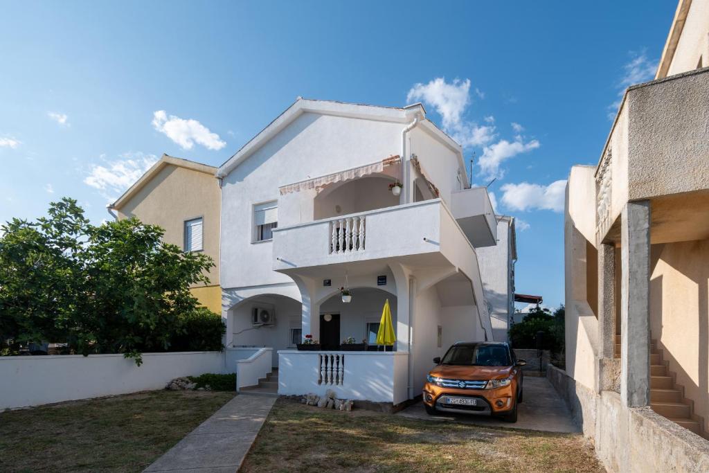 a white house with a car parked in the driveway at Apartments with a parking space Povljana, Pag - 11516 in Povljana