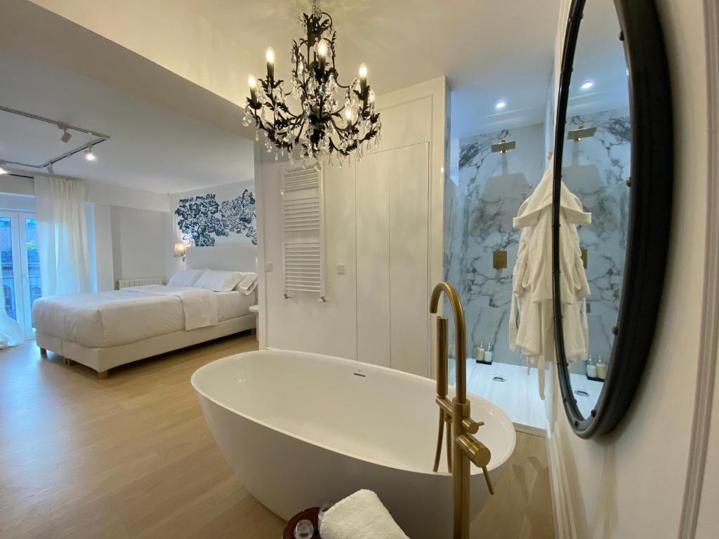 een badkamer met een bad en een slaapkamer met een bed bij Apartamentos BEJAR - INDIGO in Béjar
