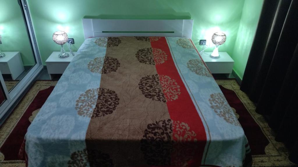 Bett in einem Zimmer mit zwei Lampen an zwei Tischen in der Unterkunft 2 minutes a l'aéroport in Marrakesch