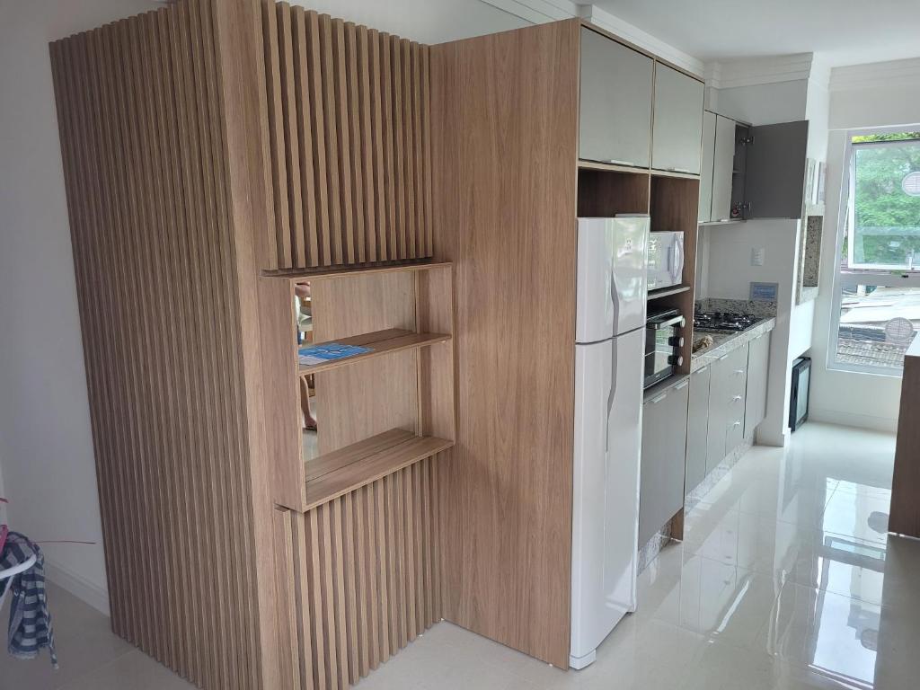 a kitchen with a wooden partition with a refrigerator at Glamour Meia Praia in Itapema