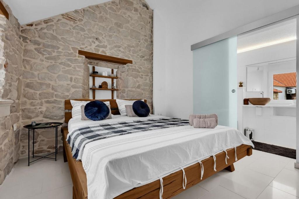 ein Schlafzimmer mit einem großen Bett und einer Steinmauer in der Unterkunft Apartments by the sea Makarska - 21443 in Makarska