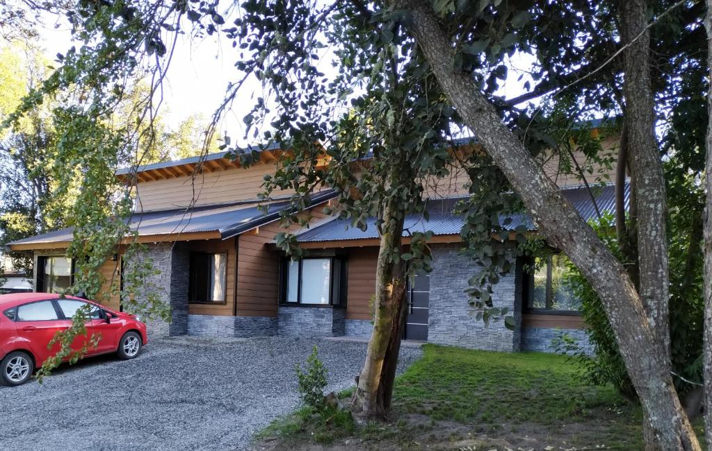 ein Haus mit einem roten Auto, das davor geparkt ist in der Unterkunft Casa de montaña con vistas al lago y a los cerros in Villa La Angostura