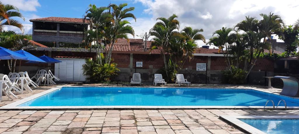 a swimming pool in front of a house with palm trees at Casa Frio da Serrinha Gravatá in Gravatá