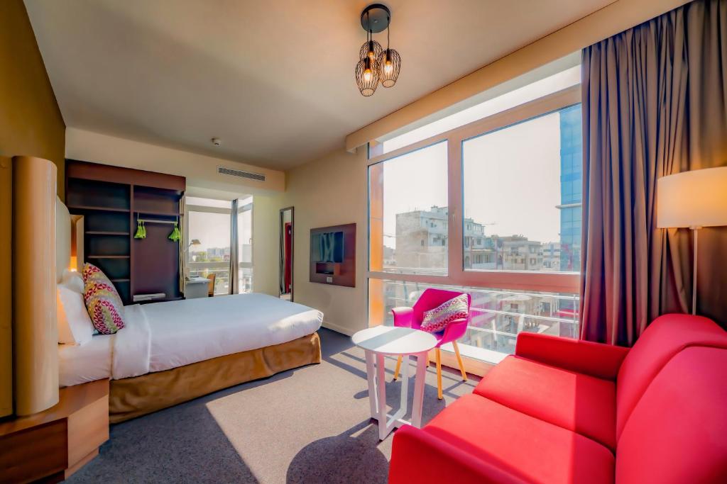 una camera d'albergo con un letto e un divano rosso di Campanile Casablanca Centre Ville a Casablanca