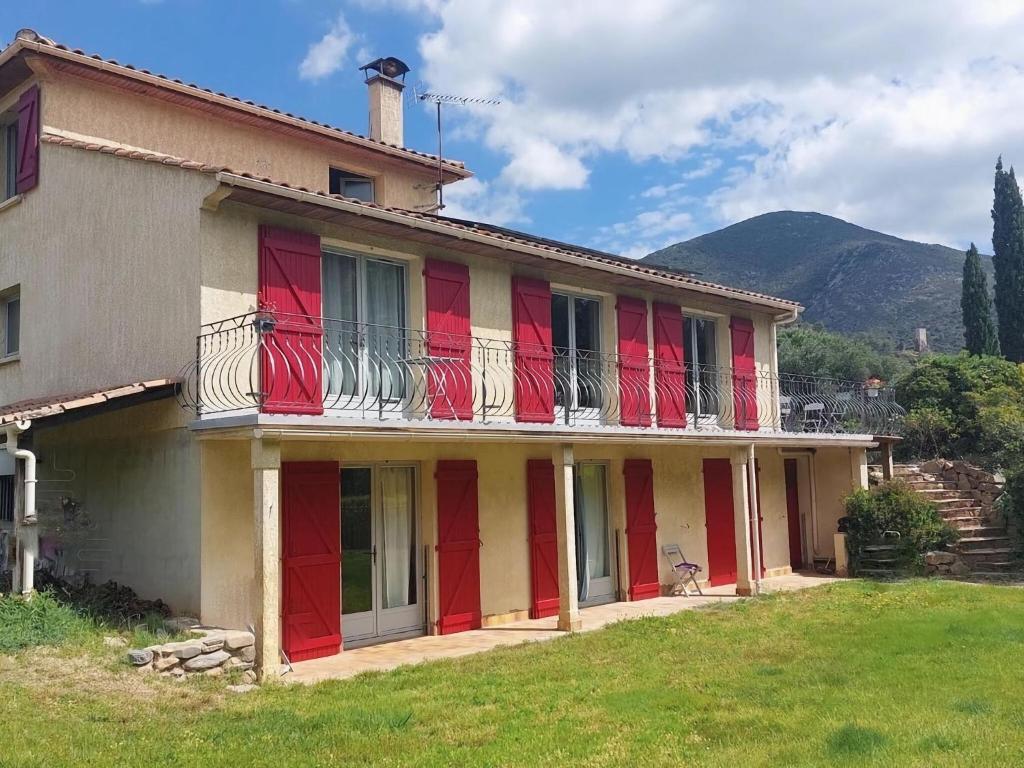 een huis met rode en witte deuren en een berg bij villa with private swimming pool in Roquebrun