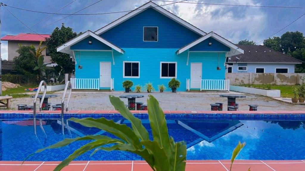 una casa azul con una piscina frente a ella en Membunga Village, en Kota Bharu