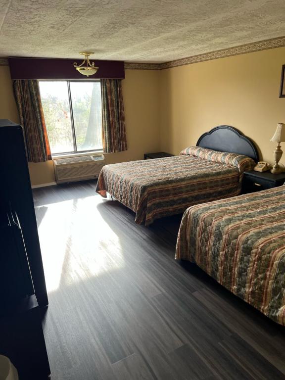 ein Hotelzimmer mit 2 Betten und einem Fenster in der Unterkunft Chateau Royale Inn in Lake Geneva