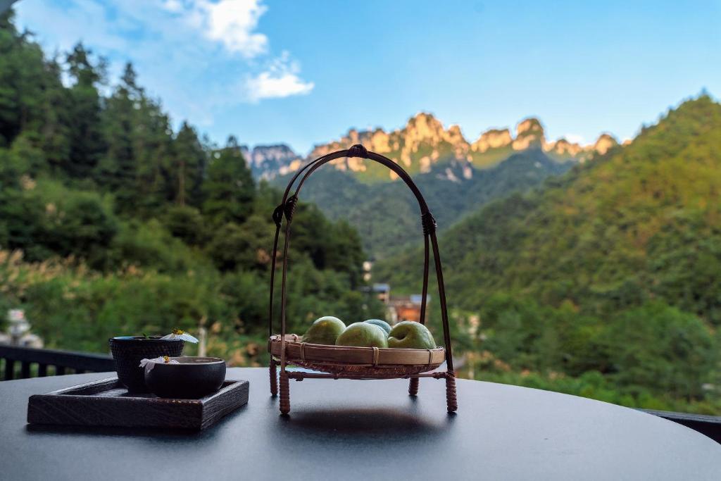- une corbeille de fruits sur une table avec vue sur les montagnes dans l'établissement National Forest Park(Yangjiajie ) MINI Inn, à Zhangjiajie