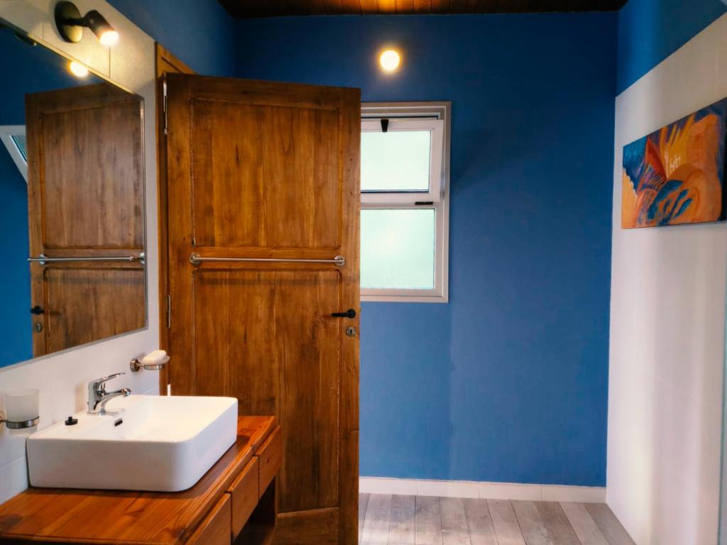 uma casa de banho com um lavatório branco e uma parede azul em Chacras casa Armonia em Chacras de Coria