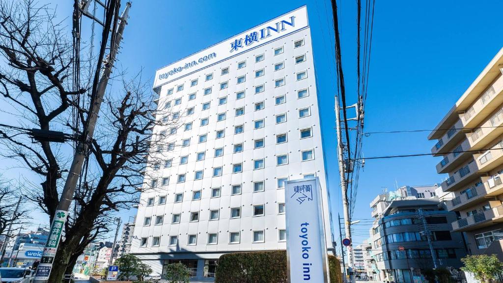 un edificio blanco con un cartel delante en Toyoko Inn Tokyo Seibu Ikebukuro sen Higashi kurume eki Nishi guchi en Higashikurume