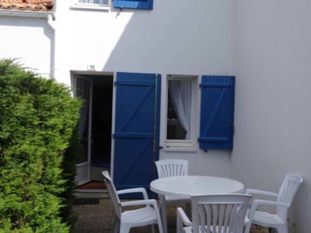 d'une terrasse avec des portes bleues, une table et des chaises. dans l'établissement Maison La Faute-sur-Mer, 2 pièces, 4 personnes - FR-1-476-203, à La Faute-sur-Mer