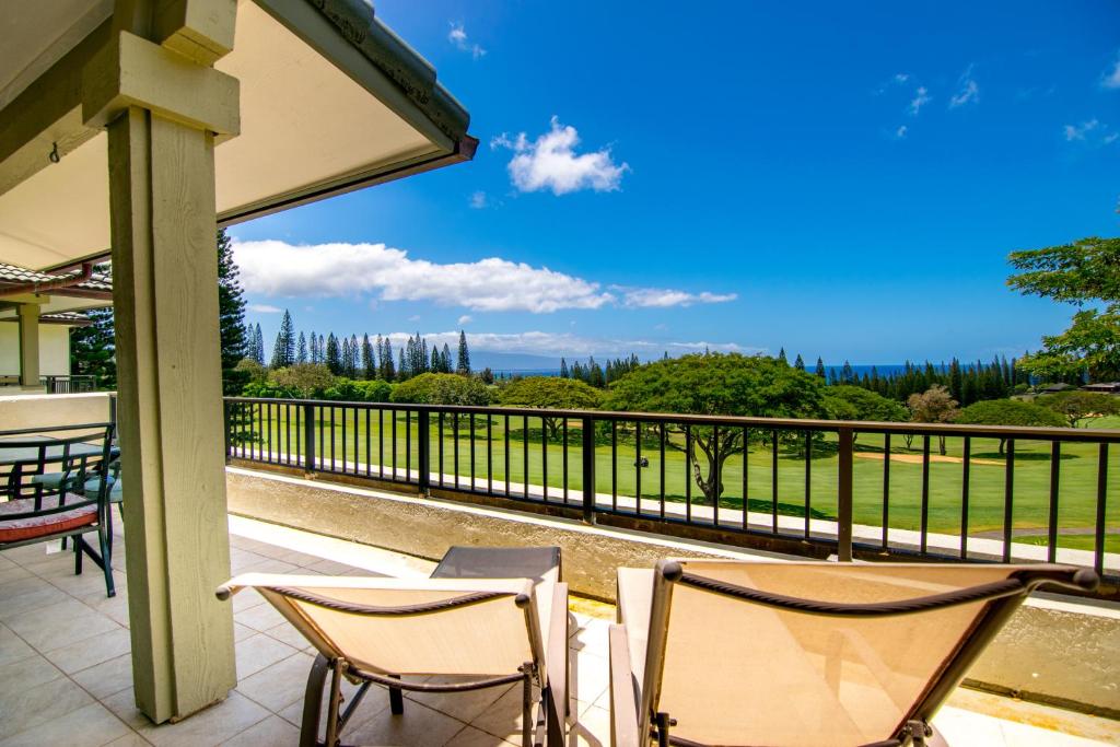 einen Balkon mit 2 Stühlen und Blick auf ein Feld in der Unterkunft Kapalua Golf Villa 16V 2 in Kahana