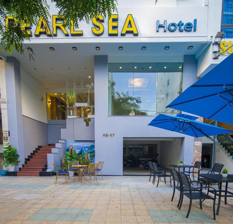 a star sea hotel with tables and chairs and blue umbrellas at Pearl Sea Hotel in Danang