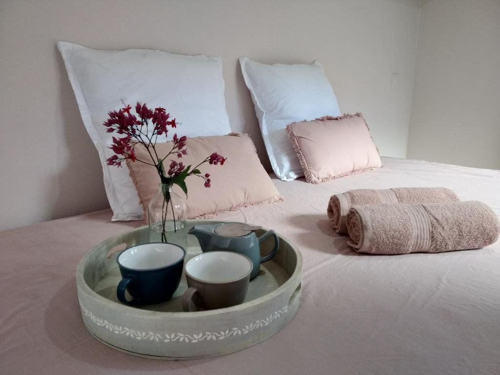 een dienblad met bekers en een vaas met bloemen op een bed bij Chalet Ohana, airport family house in Faaa