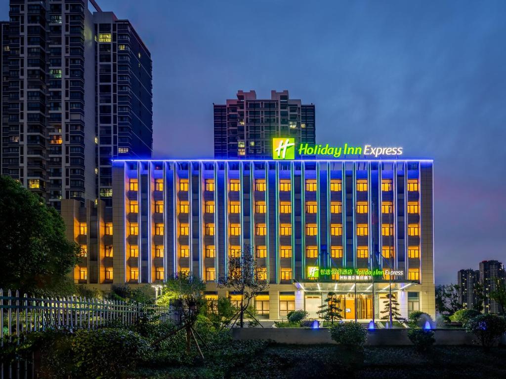 a hotel building with a blue lit up sign on it at Holiday Inn Express Jurong Xianlin in Zhenjiang