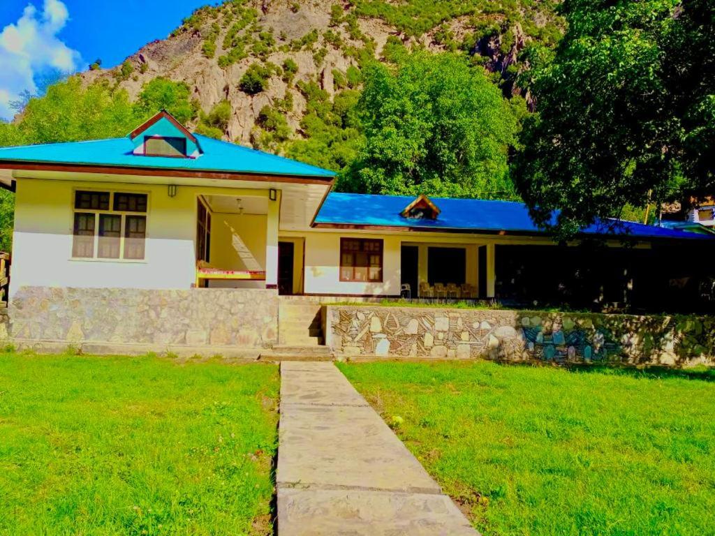 Chitral Inn Resort (Kalash Valley) في شيترال: منزل أصفر صغير بسقف أزرق