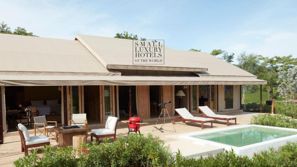 Ban Sathani Bandai MaMarasca Khao Yai - Eco-friendly Glamping Escape Near National Park的一座带游泳池、椅子和消防栓的建筑