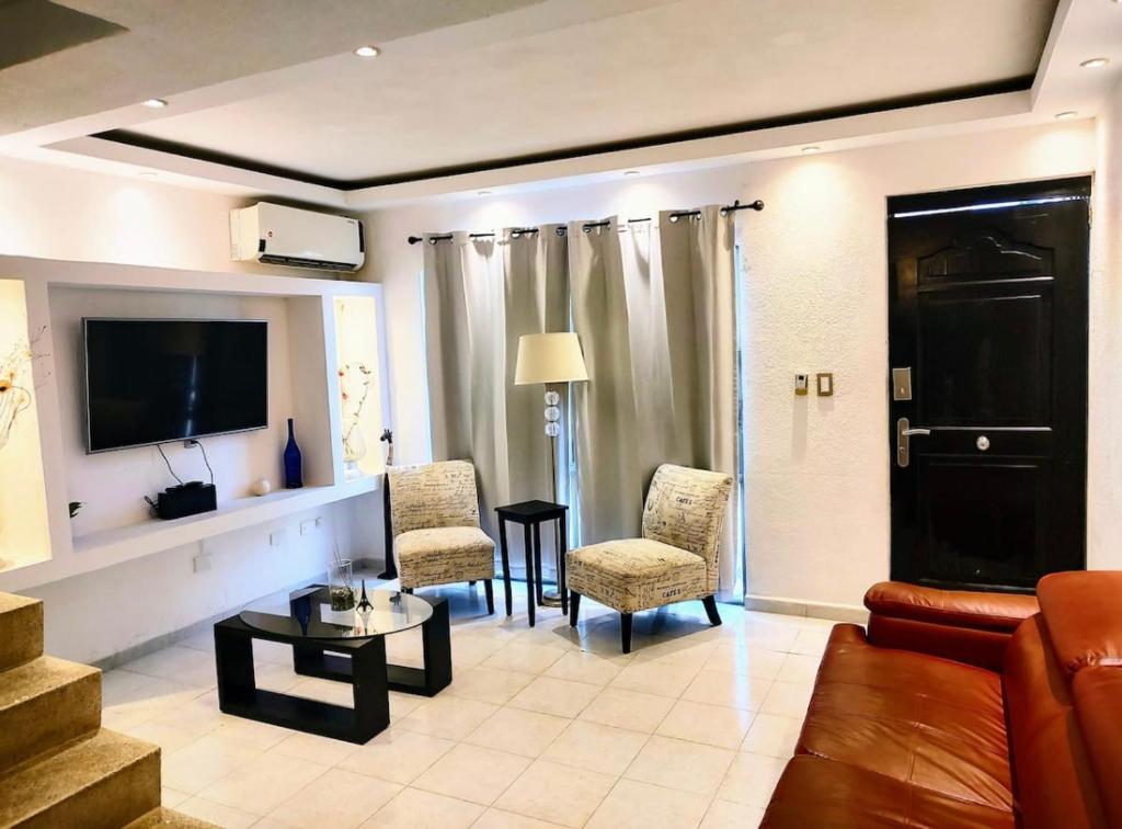 坎昆的住宿－Casa de Cielo y Mar en Cancún，客厅配有沙发、椅子和电视