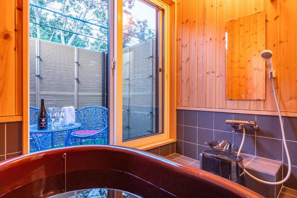 a bathroom with a tub and a table and a window at HP House Shirahama in Shirahama