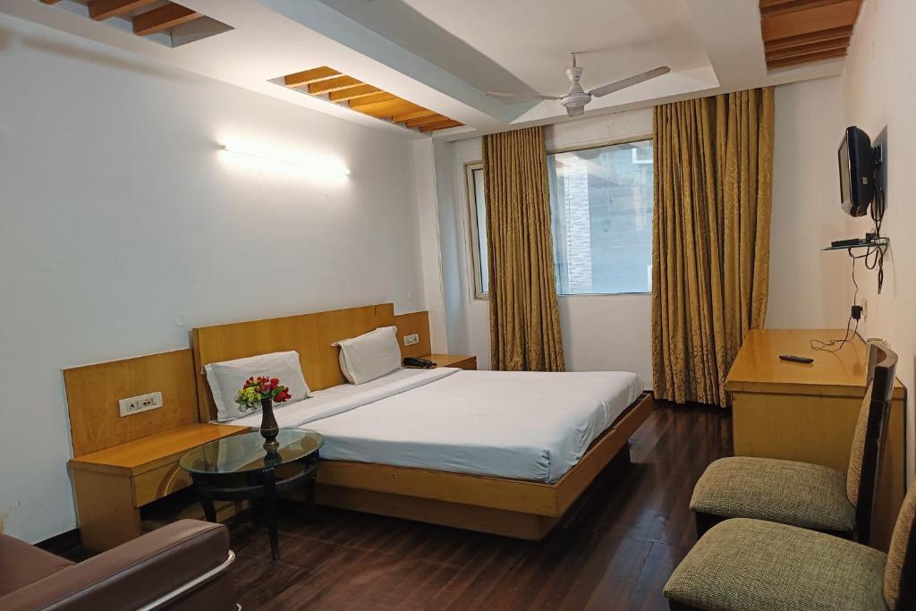 um quarto com uma cama, uma mesa e uma cadeira em Hotel Gauranga em Nova Deli