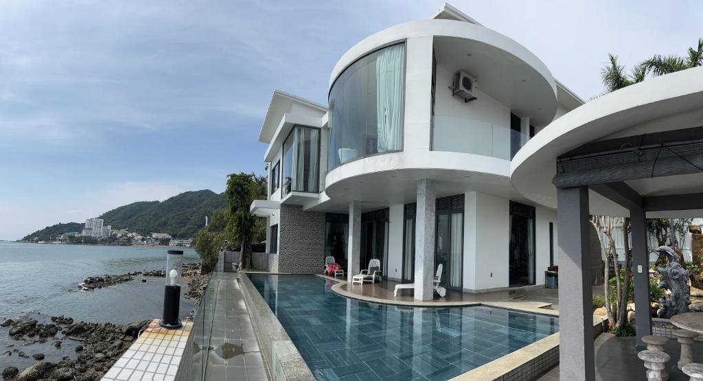 a house with a swimming pool next to the water at Nancy Tran Grand Strip Vung Tau Villa 6 in Vung Tau