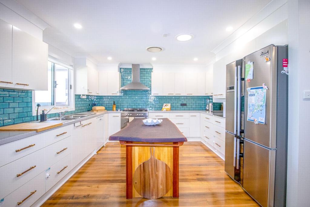 a kitchen with white cabinets and a refrigerator at A Wave from it All in Berrara