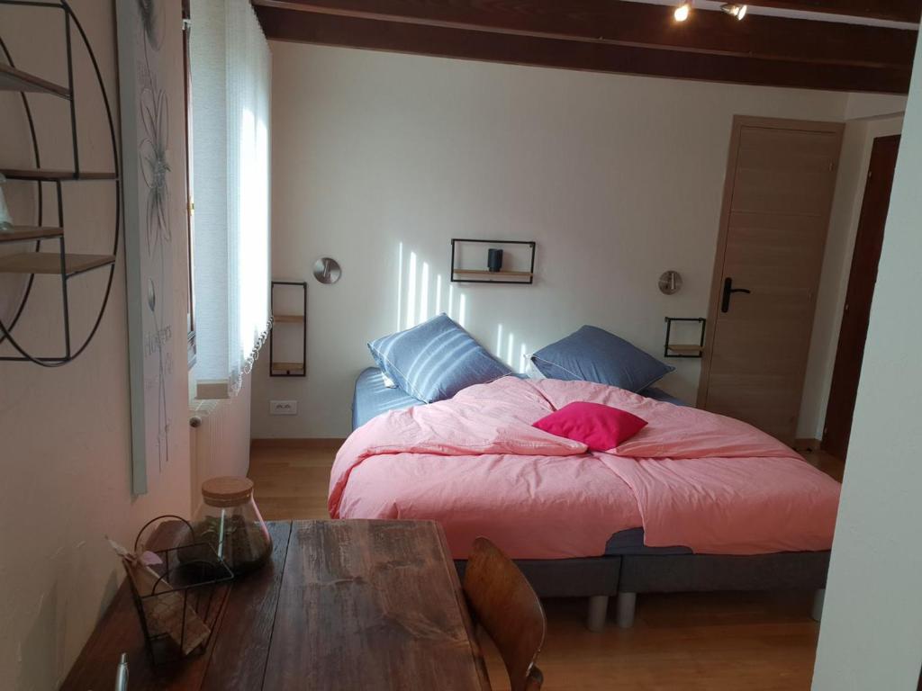 a bedroom with a bed with a pink comforter and a table at Guestroom Ventron, 1 pièce, 3 personnes - FR-1-589-567 in Ventron