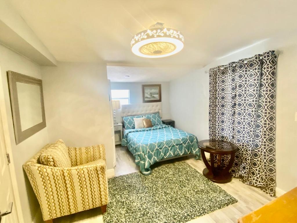a bedroom with a bed and a chair and a chandelier at Private Retreat in Lake Worth