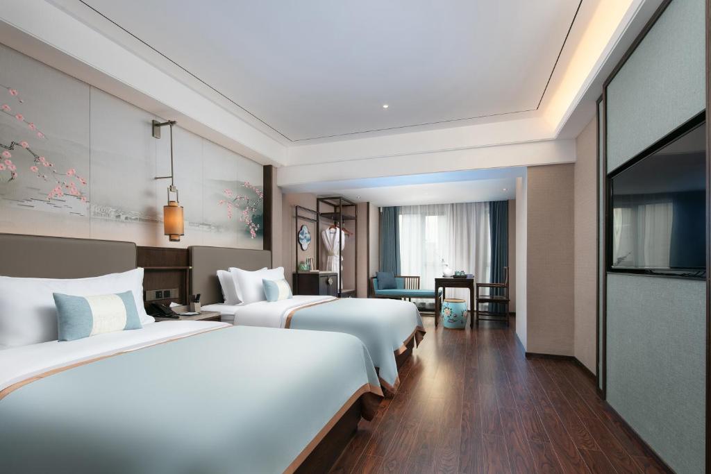 a hotel room with two beds and a television at Till Bright Hotel, Changsha Provincial Museum in Changsha
