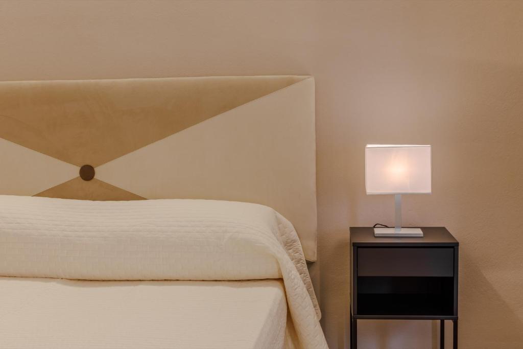 Dormitorio con cama y mesita de noche con lámpara en Albergo Alassio en Montecatini Terme