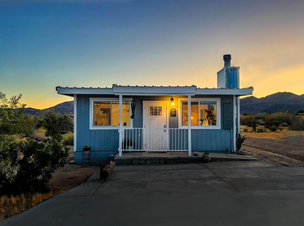 a blue tiny house in the middle of the desert at The Raven House - Renovated Homestead Cabin in Joshua Tree