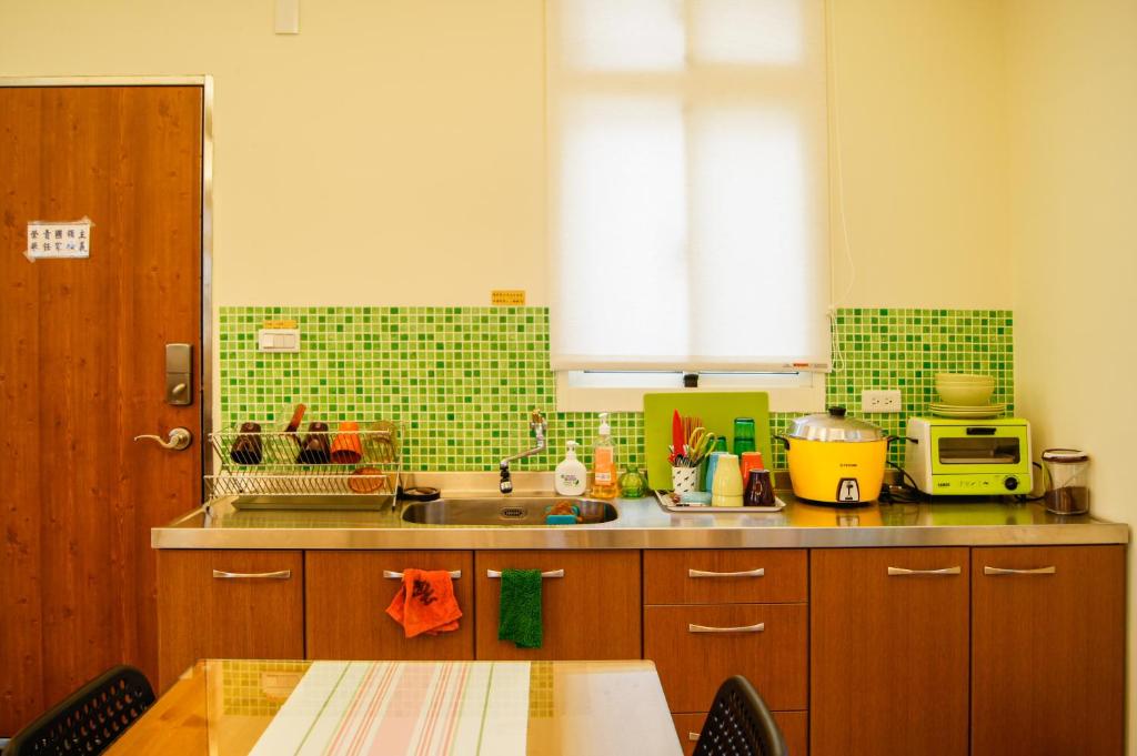 a kitchen with a sink and a counter top with a table at Happy Tree Hostel in Jinning