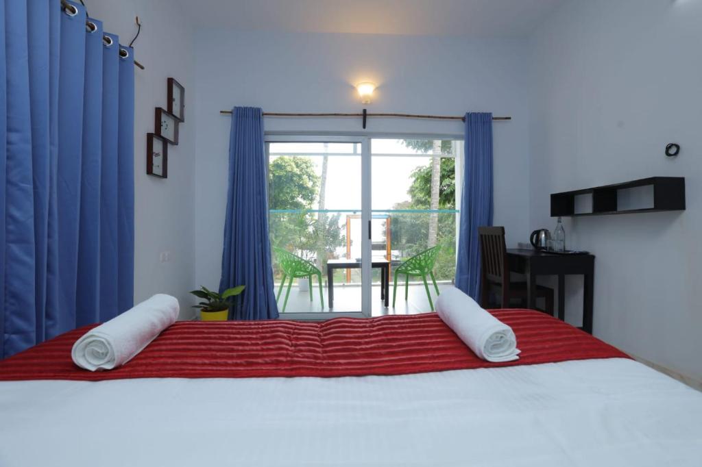 a bedroom with a large bed with blue curtains and a window at Sky Frame Beach Resort in Varkala