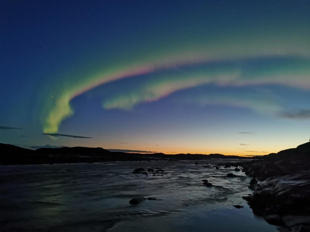 un arco iris en el cielo sobre un cuerpo de agua en Grant Arctic Escape, en Iqaluit