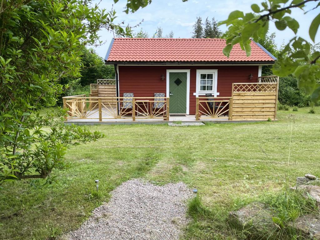 uma casa vermelha com um deque e um quintal em Newly built cozy cottage on the east side of Öland em Färjestaden